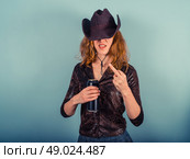 A young woman wearing a cowboy hat is drinking from a beer can and displaying rude gesture. Стоковое фото, агентство Ingram Publishing / Фотобанк Лори
