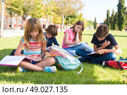 Group of little students sitting on the grass at school. Стоковое фото, агентство Ingram Publishing / Фотобанк Лори