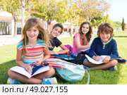 Group of little students sitting on the grass at school. Стоковое фото, агентство Ingram Publishing / Фотобанк Лори