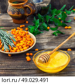Medicinal the decoction of buckthorn berries. Ripe berries of sea buckthorn in  saucer on wooden background. Стоковое фото, агентство Ingram Publishing / Фотобанк Лори
