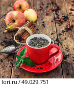 brew tea. Cup of brewed herbal tea on wooden background strewn with tea leaves. Стоковое фото, агентство Ingram Publishing / Фотобанк Лори