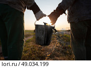 Workers carry a bucket of spilled extracted oil. Discover oil fields. Black gold. Стоковое фото, фотограф Лазаренко Светлана / Фотобанк Лори