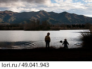 Two boys silhouetted against a mountain lake. Стоковое фото, агентство Ingram Publishing / Фотобанк Лори