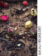 by spilling tea spoons. varieties of dry tea infuser scattered on wooden table. Стоковое фото, агентство Ingram Publishing / Фотобанк Лори
