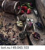 by spilling tea spoons. varieties of dry tea infuser scattered on wooden table. Стоковое фото, агентство Ingram Publishing / Фотобанк Лори