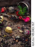 by spilling tea spoons. varieties of dry tea infuser scattered on wooden table. Стоковое фото, агентство Ingram Publishing / Фотобанк Лори