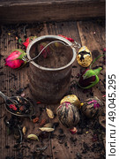 A variety of types of tea. Tea strainer on  wooden background strewn with several types of tea infuser. Стоковое фото, агентство Ingram Publishing / Фотобанк Лори