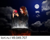 Young witch with red potion and cauldron on night sky background. Стоковое фото, агентство Ingram Publishing / Фотобанк Лори