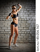 Muscular woman on grey brick wall (normal version) Стоковое фото, агентство Ingram Publishing / Фотобанк Лори