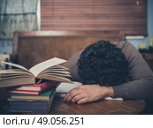 A tired student is asleep with his head on a coffee table surrounded by books. Стоковое фото, агентство Ingram Publishing / Фотобанк Лори