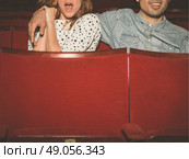 A young couple is watching a film in a movie theater, the woman is scared but her partner is looking relaxed. Стоковое фото, агентство Ingram Publishing / Фотобанк Лори