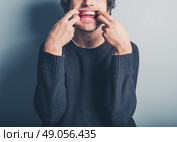 A young man wearing a black sweater is pulling silly faces. Стоковое фото, агентство Ingram Publishing / Фотобанк Лори
