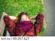 A young woman is sleeping on a bench in the park with a scarf covering her face. Стоковое фото, агентство Ingram Publishing / Фотобанк Лори