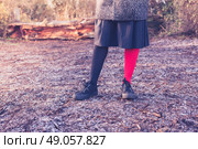 A young woman is wearing odd leggings and is standing on the frosty ground in a forest on a winter day. Стоковое фото, агентство Ingram Publishing / Фотобанк Лори