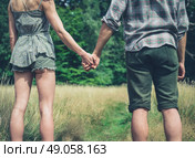 A young couple is standing in a meadow in the forest and holding hands. Стоковое фото, агентство Ingram Publishing / Фотобанк Лори