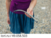 A young woman is standing on a pebbled river bank with a bone she has found beach combing. Стоковое фото, агентство Ingram Publishing / Фотобанк Лори