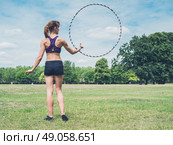 A fit and athletic young woman is twirling a hula hoop in the park on a sunny summer day. Стоковое фото, агентство Ingram Publishing / Фотобанк Лори