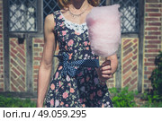 A young woman wearing a dress is standing outside an old farmhouse with a candyfloss on a sunny summer day. Стоковое фото, агентство Ingram Publishing / Фотобанк Лори