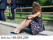 A young woman wearing a dress is sitting outside on a farm with smartly dressed people participating in a social event or gathering. Стоковое фото, агентство Ingram Publishing / Фотобанк Лори