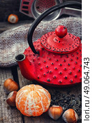 Cast iron kettle red,tangerine,tea leaves on wooden background. Стоковое фото, агентство Ingram Publishing / Фотобанк Лори
