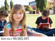 Group of little students sitting on the grass at school. Стоковое фото, агентство Ingram Publishing / Фотобанк Лори