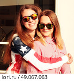 Close up fashion portrait of two young hipster girl friends, wearing mirrored sunglasses, having blonde and ombre hairs. Стоковое фото, агентство Ingram Publishing / Фотобанк Лори
