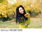 Excited happy fall woman smiling joyful and blissful holding autumn leaves outside in colorful fall forest. Young woman in beautiful autumn park, concept autumn. Стоковое фото, агентство Ingram Publishing / Фотобанк Лори