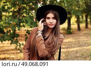 Street fashion concept - closeup portrait of a pretty girl. Wearing hat and suede jacket holding bag with fringe. Beautiful autumn woman. . Стоковое фото, агентство Ingram Publishing / Фотобанк Лори