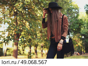 Street fashion concept - closeup portrait of a pretty girl. Wearing hat and suede jacket holding bag with fringe. Beautiful autumn woman. . Стоковое фото, агентство Ingram Publishing / Фотобанк Лори