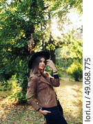 Street fashion concept - closeup portrait of a pretty girl. Wearing hat and suede jacket holding bag with fringe. Beautiful autumn woman. . Стоковое фото, агентство Ingram Publishing / Фотобанк Лори