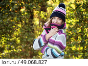 Portrait of a funny young girl in the autumn weather in warm clothes, scarf and hat. Young woman in forest in fall colors. Стоковое фото, агентство Ingram Publishing / Фотобанк Лори