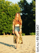 Fashion portrait of beautiful hippie young woman wearing boho chic clothes, chiffon cardigan and boho chic style bijouterie. Blonde haired woman dressed in bohemian style at the beach. Стоковое фото, агентство Ingram Publishing / Фотобанк Лори