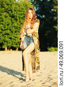 Fashion portrait of beautiful hippie young woman wearing boho chic clothes, chiffon cardigan and boho chic style bijouterie. Blonde haired woman dressed in bohemian style at the beach. Стоковое фото, агентство Ingram Publishing / Фотобанк Лори
