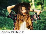 Fashion portrait of beautiful hippie young woman wearing boho chic clothes and summer hat outdoors. Soft warm vintage color tone. Artsy bohemian style. Стоковое фото, агентство Ingram Publishing / Фотобанк Лори