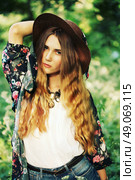 Fashion portrait of beautiful hippie young woman wearing boho chic clothes and summer hat outdoors. Soft warm vintage color tone. Artsy bohemian style. Стоковое фото, агентство Ingram Publishing / Фотобанк Лори