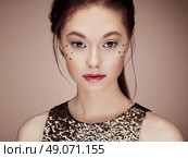 Portrait of beautiful young woman in a shiny golden dress. Brunette girl. Perfect make-up. Freckles. Стоковое фото, агентство Ingram Publishing / Фотобанк Лори