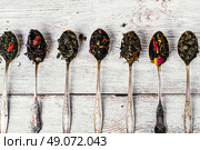 Seven kinds of tea infuser in tea spoons on wooden background. Varieties of teas. Стоковое фото, агентство Ingram Publishing / Фотобанк Лори