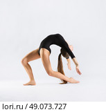 Young girl engaged art gymnastic on grey. Стоковое фото, агентство Ingram Publishing / Фотобанк Лори