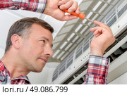 Electrician fitting an air conditioning unit. Стоковое фото, агентство Ingram Publishing / Фотобанк Лори