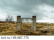 Broken gate on a field with barb wire in cloudy weather. Стоковое фото, агентство Ingram Publishing / Фотобанк Лори
