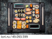 Sushi Set: maki, nigiri , ouside rolls  served with  soy sauce , pickled ginger and wasabi on dark wooden plate on rustic background, top view. Стоковое фото, агентство Ingram Publishing / Фотобанк Лори