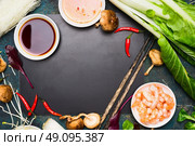 Chinese or Thai cooking food background. Asian food ingredients : soy sauce, chopsticks, rice noodles , pok choi,  shiitake mushrooms and scampi on black blank chalkboard, top view. Стоковое фото, агентство Ingram Publishing / Фотобанк Лори
