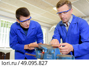 Two engineers working on copper tube held in a vice. Стоковое фото, агентство Ingram Publishing / Фотобанк Лори