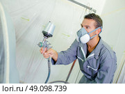 Young mechanic spray painting a car. Стоковое фото, агентство Ingram Publishing / Фотобанк Лори
