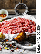 meat ground in meat grinder. Minced meat and parts of meat grinder on wooden table in rustic style. Стоковое фото, агентство Ingram Publishing / Фотобанк Лори