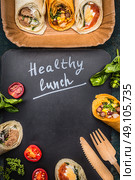 Healthy lunch Lettering  with vegetarian wraps and wooden cutlery on dark chalkboard, top view, frame. Стоковое фото, агентство Ingram Publishing / Фотобанк Лори