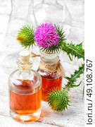 Elixir of medicinal herbs. Glass vial with therapeutic drug of the flowering milk Thistle. Стоковое фото, агентство Ingram Publishing / Фотобанк Лори