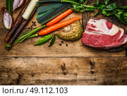 Beef brisket with vegetables ingredients for soup or broth cooking on rustic wooden background, top view, border. Стоковое фото, агентство Ingram Publishing / Фотобанк Лори