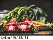 Beef Ox tail meat with bone and cooking ingredients for soup or broth on rustic kitchen table. Стоковое фото, агентство Ingram Publishing / Фотобанк Лори