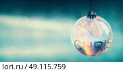 Transparent Christmas ball with shine and bokeh on blue light background, banner. Стоковое фото, агентство Ingram Publishing / Фотобанк Лори